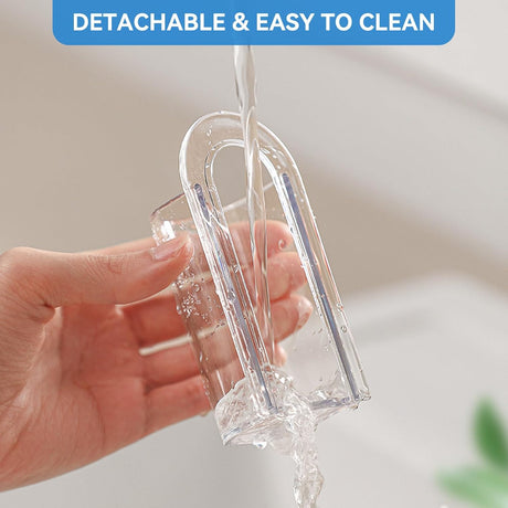 Clear toothbrush holder cylinder lifted off its adhesive base ready for rinsing