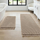Cream waffle bath mat set of two with tassels laid on a bathroom floor
