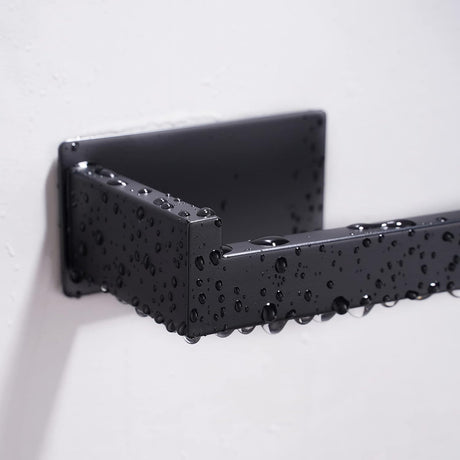 Black toilet roll holder loaded with a paper roll on a tiled bathroom wall
