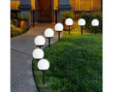 Cool white solar globe stake lights lining a garden pathway at dusk