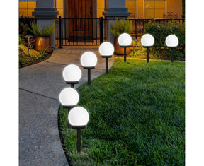 Cool white solar globe stake lights lining a garden pathway at dusk