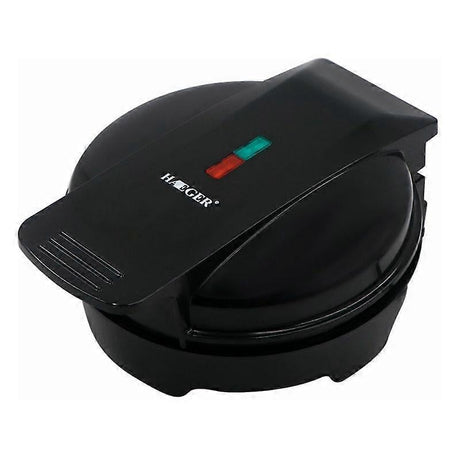 Mini waffle maker closed on a kitchen bench with indicator light on the lid