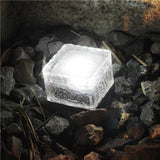 Frosted ice cube solar ground light set into a patio surface at night