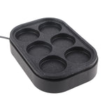 Six hole pan on a cooktop with eggs cooking