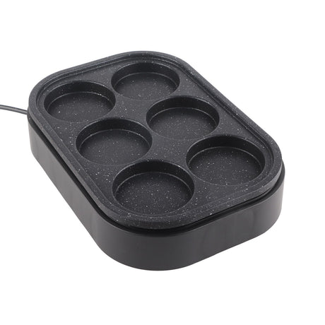 Six hole pan on a cooktop with eggs cooking