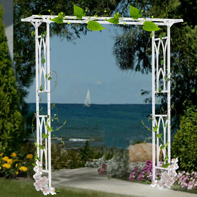 White metal garden arch arbour standing on lawn in a landscaped garden