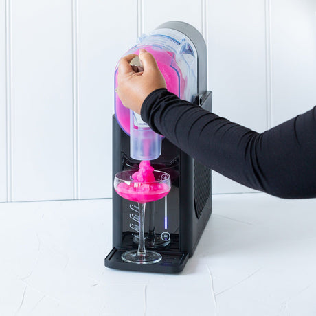 Juice being poured into the slushie maker between the minimum and maximum fill