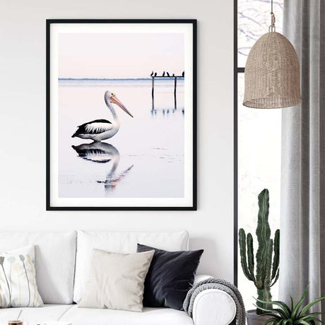 Black framed pelican canvas print styled on a coastal interior wall