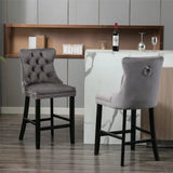 Waterways grey velvet bar stool with silver stud trim and wooden legs in a dining room