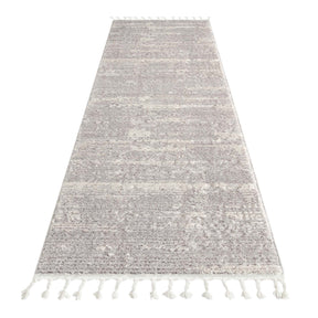 Bukhara light grey plush area rug with sculpted pile and tassels in a calm bedroom