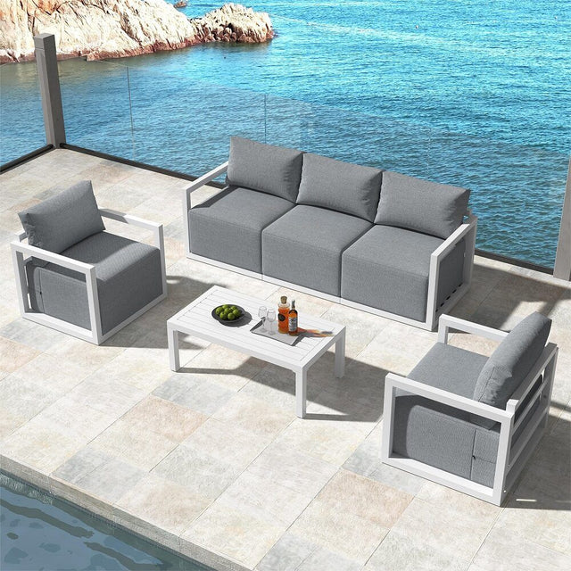 White deep seated rattan outdoor lounge set with thick cushions on a patio