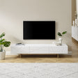 Oatlands gloss white TV cabinet with linear design and gold metal base in a living room