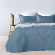 Blue paisley embossed coverlet with two pillowcases on a Queen King bed