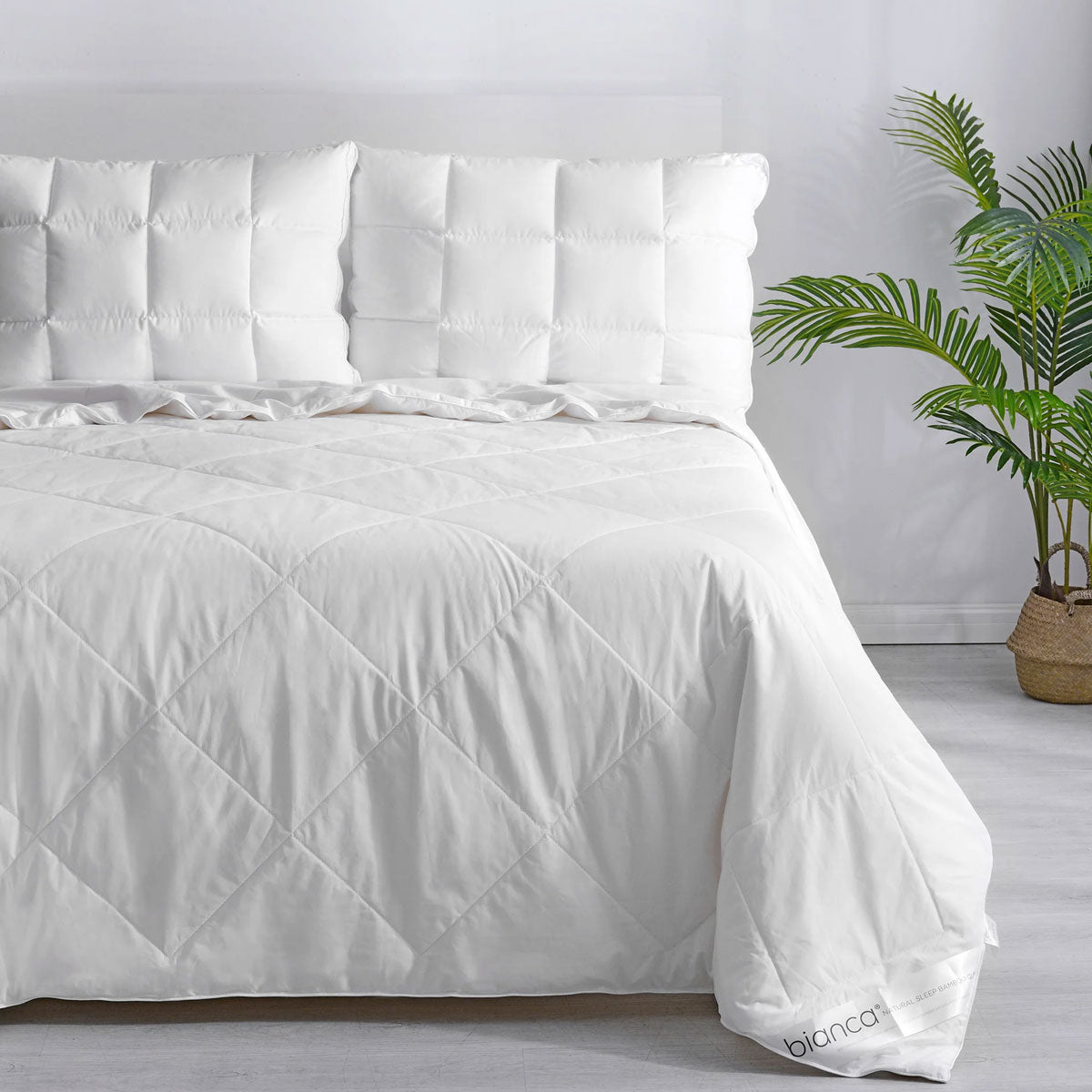 Diamond quilted bamboo blend summer quilt in white on a made queen bed