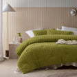 Green comforter set with a geometric parquet print and two pillowcases on a queen bed