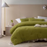 Green comforter set with a geometric parquet print and two pillowcases on a queen bed