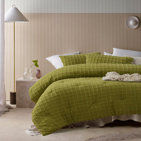 Green comforter set with a geometric parquet print and two pillowcases on a queen bed