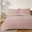 Blush ultrasonic embossed reversible coverlet with two pillowcases on a King bed