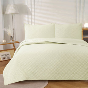 Light cream ultrasonic embossed reversible coverlet with two pillowcases on a King bed