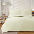 Light cream ultrasonic embossed reversible coverlet with two pillowcases on a Queen bed