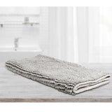 Large silver microfibre bath mat with a toggle applique design on a bathroom floor