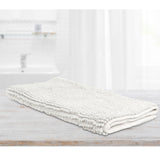 White microfibre bath mat with applique design on a tiled bathroom floor