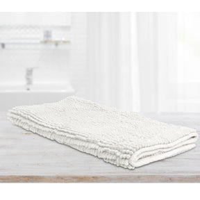 White microfibre bath mat with applique design on a tiled bathroom floor