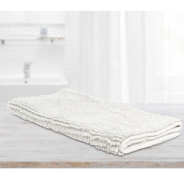 White microfibre bath mat with applique design on a tiled bathroom floor