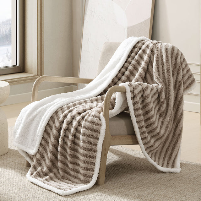 Stawell striped boucle throw rug with sherpa reverse draped over a sofa