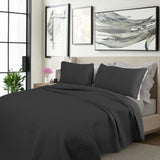 Charcoal embroidered cooling comforter with two pillowcases on a Queen bed