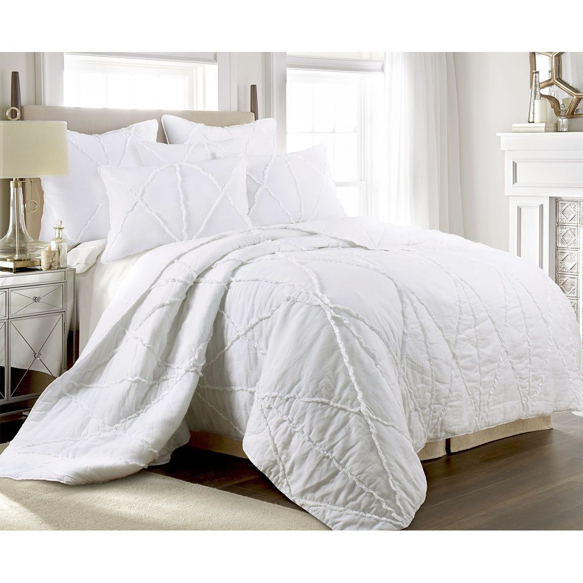 White cotton coverlet set with tiered ruffles and two pillow shams on a queen bed