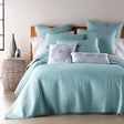 Blue cotton coverlet set with a pompom trim and two pillow shams on a queen bed