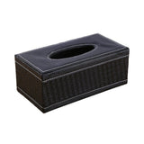 Black woven tissue box cover on a bedside table beside a lamp