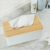 White tissue box with a tissue drawn up through the opening in the timber lid