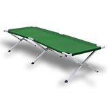 Green folding camp stretcher bed with aluminium frame raised off the ground