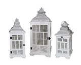 Set of three rustic white wooden candle lanterns with metal roofs in graduated heights