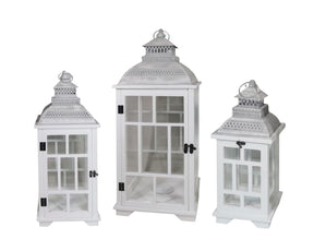 Set of three rustic white wooden candle lanterns with metal roofs in graduated heights