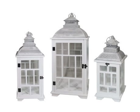 Set of three rustic white wooden candle lanterns with metal roofs in graduated heights