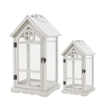 Set of two white house shaped wooden lanterns with glass panels and pitched roofs