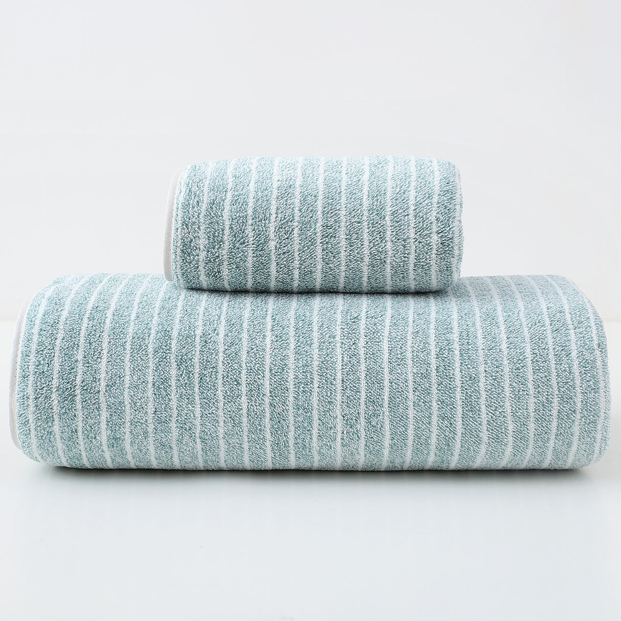 Green striped cotton towels folded and stacked showing woven stripe detail