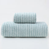 Green striped cotton towels folded and stacked showing woven stripe detail