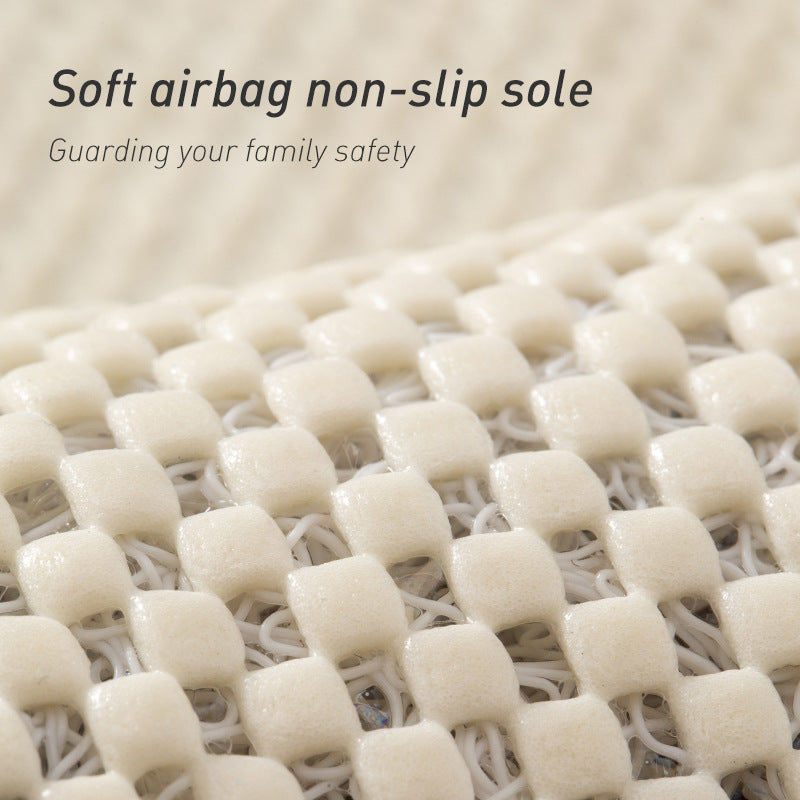 Grey loofah bath mat placed beside a shower on a tiled bathroom floor