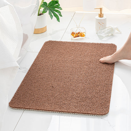 Brown loofah texture bath mat, 40 x 60 cm, laid on a bathroom floor