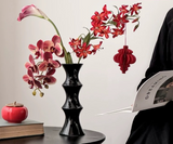 Tall glossy black bamboo form ceramic vase on a dining table