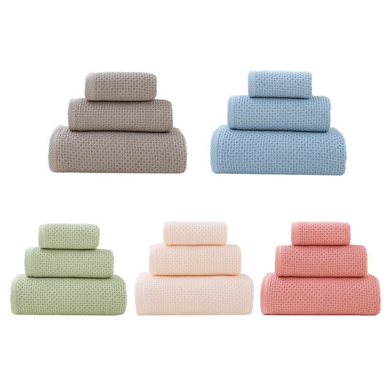 Light pink waffle weave cotton bath towel folded on a bathroom bench