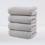 Four pack of light grey plush cotton hand towels stacked together