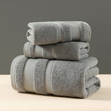 Grey three piece cotton towel set with bath towel, hand towel and face washer folded in a stack