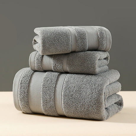 Grey three piece cotton towel set with bath towel, hand towel and face washer folded in a stack