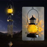Wrought iron solar pineapple wind chime light hanging from a garden tree
