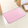 Pink absorbent bath mat, 40 x 120 cm, with short plush pile laid beside a bath